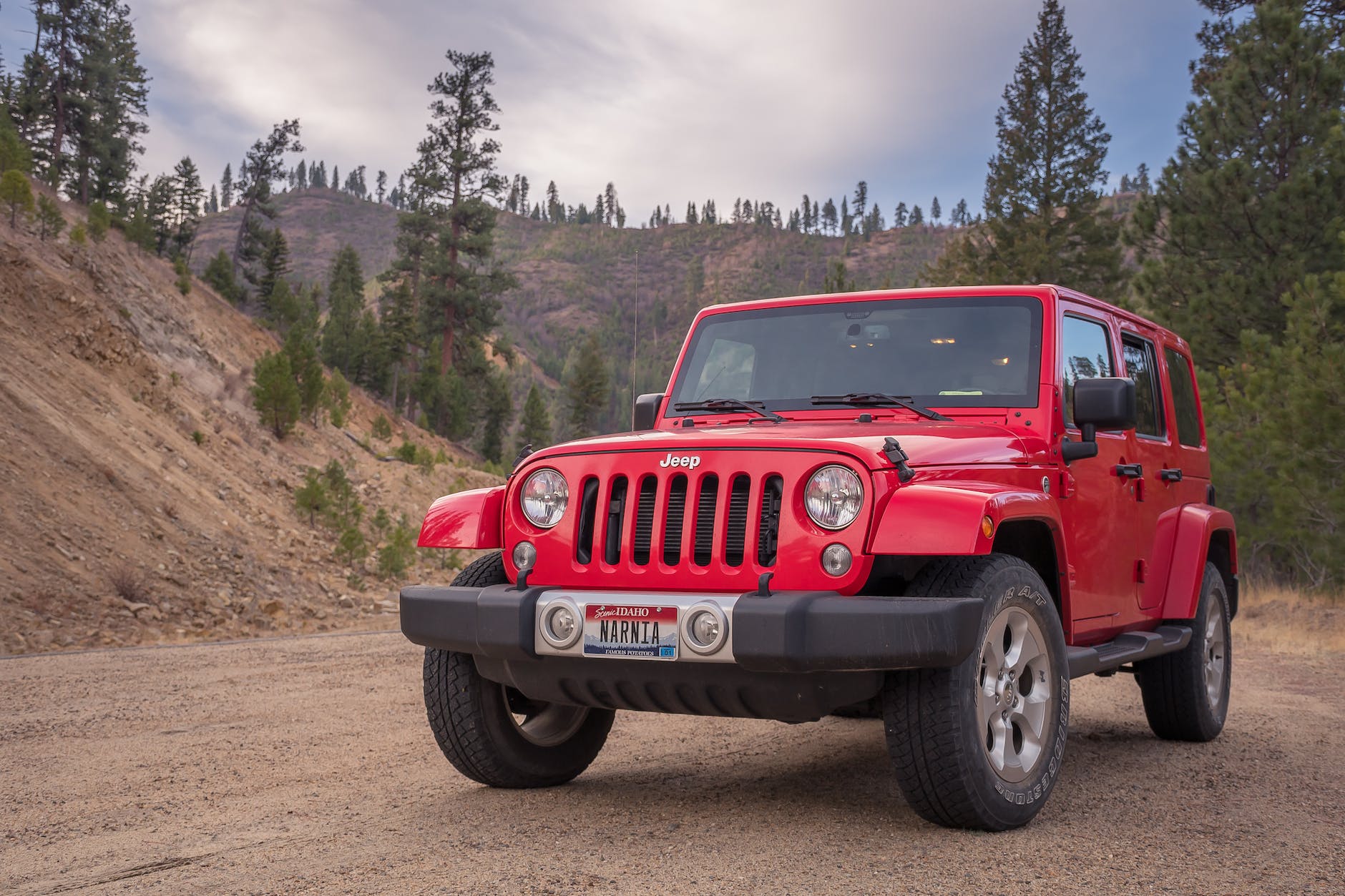 red jeep parked in the middle of a dirt road