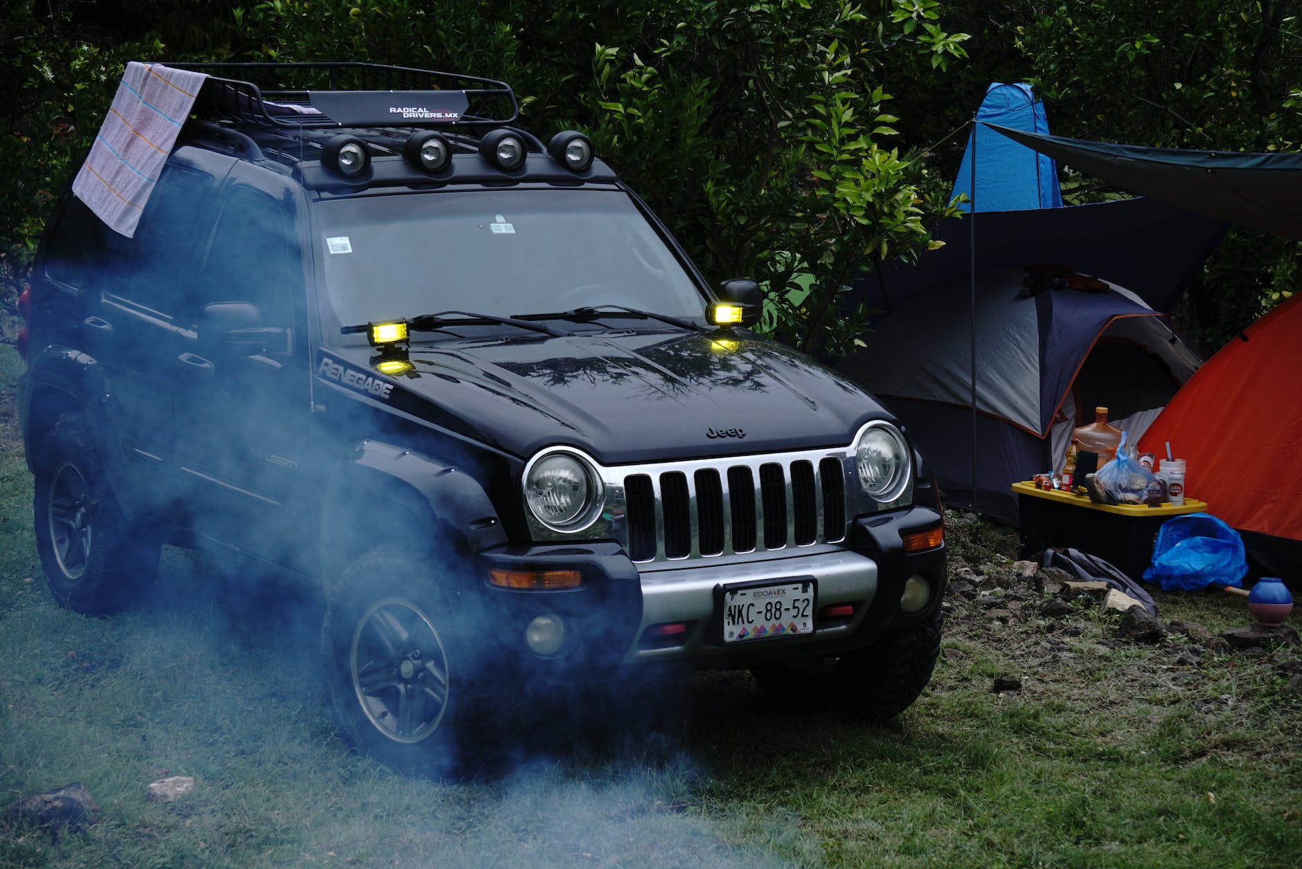 jeep by tents in forest